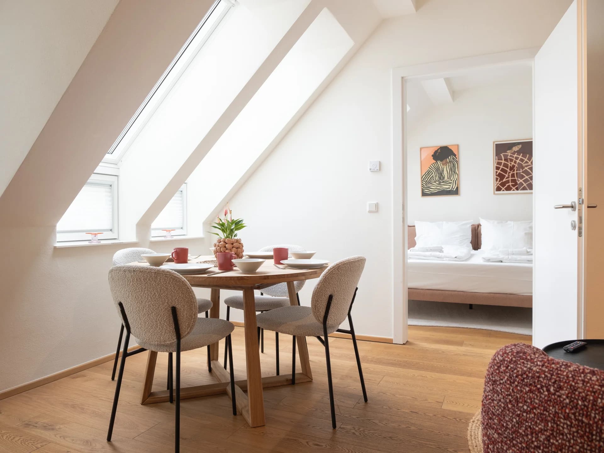 A MINT apartment under the Vienna roofline: dining table beneath the skylights, bedroom through the open door.